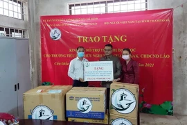 Ông Trần Đức Hiển, Phó Chủ nhiệm Ủy ban về Người Việt Nam ở nước ngoài TP.HCM (ngoài cùng, bên trái) trao tượng trưng kinh phí cho đại diện trường Tiểu học Hữu nghị tỉnh Champasak của Lào. (Ảnh: TTXVN phát)