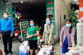 Đại diện Liên đoàn Lao động Thành phố Hồ Chí Minh trao quà cho công nhân lao động gặp khó khăn đang ở trọ tại phường Bình Thọ, thành phố Thủ Đức. (Ảnh: Thanh Vũ/TTXVN)