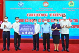 Bộ trưởng Bộ Thông tin và Truyền thông Nguyễn Mạnh Hùng (trái) trao số tiền nhắn tin 100 tỷ đồng ủng hộ Quỹ vaccine phòng COVID-19 (phân bổ đợt 1) cho Giám đốc Ban quản lý Quỹ vaccine phòng COVID-19 Nguyễn Quang Vinh. (Ảnh: Minh Đức/TTXVN)