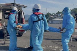 Nhân viên của Trung tâm Phối hợp tìm kiếm, cứu nạn hàng hải Việt Nam khu vực IV tại Khánh Hòa đưa bệnh nhân lên bờ để chuyển bệnh viện điều trị. (Ảnh: TTXVN phát)