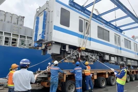 Các chuyên gia, kỹ sư, công nhân đưa toa xe xuống xe vận chuyển chuyên dụng. (Ảnh: TTXVN phát)
