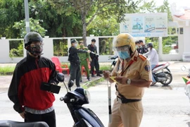 Lực lượng chức năng kiểm tra giấy tờ của một người dân. (Ảnh: Chanh Đa/TTXVN)