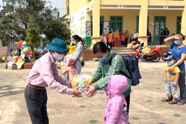 Tặng quà chúc mừng các cháu học sinh và người chăm sóc hết thời hạn cách ly và được về nhà. (Ảnh: Mạnh Tú/TTXVN)
