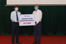 Tổng Giám đốc EVN Trần Đình Nhân trao tượng trưng tiền ủng hộ Quỹ Vaccine phòng COVID-19 cho Bộ trưởng Bộ Y tế Nguyễn Thanh Long. (Ảnh: TTXVN phát)