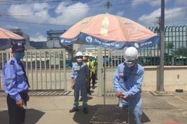 Người lao động thực hiện sát khuẩn phòng dịch COVID-19 trước khi vào làm việc. (Nguồn: baothanhhoa)