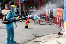 Phun thuốc tiêu độc, khử trùng tại khu vực dân cư có trường hợp dương tính với SARS-CoV-2. (Ảnh: Lê Ngọc Phước/TTXVN)