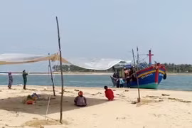 Người nhà nạn nhân và các lực lượng chức năng đưa thi thể ngư dân vào bờ. (Ảnh: TTXVN phát)