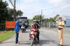 Kiểm soát người ra vào địa bàn tại chốt kiểm soát dịch bệnh ở xã Hậu Thành, huyện Cái Bè, tỉnh Tiền Giang. (Ảnh: Hữu Chí/TTXVN)