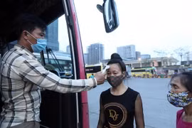 Hành khách được đo kiểm tra thân nhiệt trước khi lên xe. (Ảnh: Phan Tuấn Anh/TTXVN)