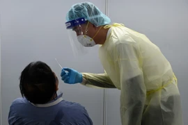 Nhân viên y tế lấy mẫu xét nghiệm COVID-19 (Ảnh: AFP/TTXVN)