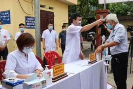 Cử tri được đo thân nhiệt, sát khuẩn tay trước khi vào bầu cử. (Ảnh: Thái Hùng/TTXVN)