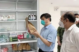 Bộ trưởng Bộ Y tế Nguyễn Thanh Long kiểm tra túi thuốc hỗ trợ điều trị cho F0 tại nhà. (Ảnh: TTXVN phát)