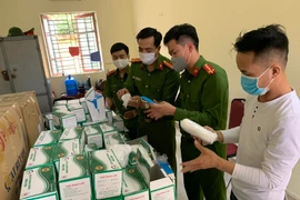 Lực lượng công an kiểm tra lô hàng khẩu trang vừa bị thu giữ. (Nguồn: TTXVN phát)