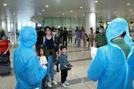 Lực lượng Công an cửa khẩu Cảng hàng không Quốc tế Nội Bài kiểm tra hộ chiếu, hướng dẫn và phát thẻ cho hành khách đi cách ly. (Ảnh: Doãn Tấn/TTXVN)