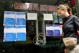 Một khách nước ngoài bước qua một khách sạn ở Hà Nội đóng cửa vì COVID-19. (Ảnh: Lâm Khánh/TTXVN)