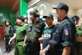 Cảnh sát dẫn giải một đối tượng đến bệnh viện khống chế người để đòi nợ. (Ảnh: Sỹ Tuyên/TTXVN)