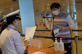 Lực lượng chức năng kiểm tra khai báo y tế của những hành khách đáp chuyến bay từ Hàn Quốc đến sân bay Cam Ranh trong chiều 25/2. (Ảnh: Nguyễn Dũng/TTXVN)