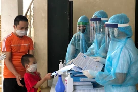 Ban chỉ huy quân sự huyện Thạch Thất phát tài liệu hướng dẫn cho trẻ em và gia đình, người chăm sóc trẻ tại khu cách ly Đại học Quốc gia Hà Nội. (Nguồn: TTXVN phát)