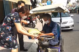 Chị Trần Thị Ngọc Hạnh - Chủ đại lý vé số Duyên (phường 1, thành phố Vĩnh Long) trao quà cho người bán vé số dạo. (Ảnh: Lê Thúy Hằng/TTXVN)