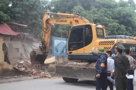 Lực lượng chức năng tiến hành tháo dỡ các công trình vi phạm. (Ảnh: Nguyễn Thắng/TTXVN)