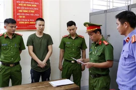 Lực lượng chức năng đọc lệnh khởi tố, bắt tạm giam phóng viên Nguyễn Trọng Hùng. (Ảnh: TTXVN phát)