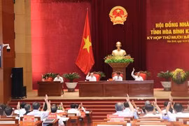 Các đại biểu HĐND tỉnh Hòa Bình biểu quyết thông qua các Nghị quyết tại kỳ họp. (Ảnh: Nhan Sinh/TTXVN)