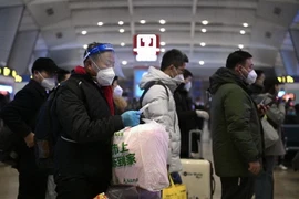 Hành khách xếp hàng chờ lên tàu tại nhà ga ở Bắc Kinh, Trung Quốc. (Ảnh: AFP/TTXVN)