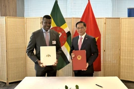 Bộ trưởng Ngoại giao Bùi Thanh Sơn và Bộ trưởng Ngoại giao, Ngoại thương, Thương mại và Năng lượng Cộng đồng Thịnh vượng Dominica Vince Henderson (đứng, bên trái) tại lễ ký. (Ảnh: Thanh Tuấn/TTXVN)