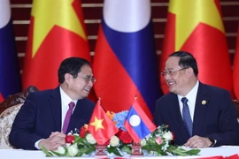 Thủ tướng Phạm Minh Chính và Thủ tướng Lào Sonexay Siphandone trao đổi tại lễ ký các văn kiện hợp tác giữa hai nước Việt Nam-Lào. (Ảnh: Dương Giang/TTXVN)