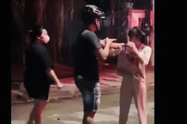 Hai người đánh cô gái mặc áo trắng. (Ảnh cắt từ clip)