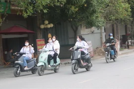 Học sinh đi xe máy điện không đội mũ bảo hiểm, dàn hàng ngang trên đường, tiềm ẩn nguy cơ mất an toàn giao thông. (Ảnh minh họa. Nguồn: TTXVN)
