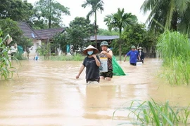 Người dân giúp nhau vận chuyển tài sản, đồ đạc để tránh lũ tại các gia đình đã bị ngập nặng. (Ảnh: Xuân Tiến/TTXVN)