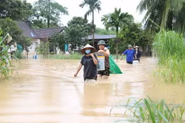 Người dân giúp nhau vận chuyển tài sản, đồ đạc để tránh lũ tại các gia đình đã bị ngập nặng. (Ảnh: Xuân Tiến/TTXVN)