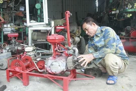 Ông Vũ Văn Dung với nông cụ do ông sáng chế. (Ảnh: Thùy Dung/TTXVN)