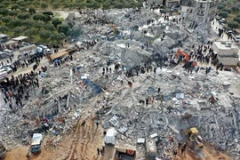 Lực lượng cứu hộ và tình nguyện viên tìm kiếm các nạn nhân và người sống sót mắc kẹt trong đống đổ nát sau động đất mạnh ở làng Besnia, gần thị trấn Harim, tỉnh Idlib, Syria, giáp giới Thổ Nhĩ Kỳ. (Ảnh: AFP/TTXVN)