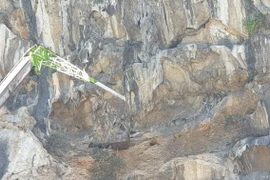 Nhà thầu di chuyển đất đá khỏi khu vực sạt lở. (Ảnh: TTXVN phát)