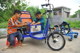 Không may bị dị tật bẩm sinh, khó khăn trong việc đi lại, nhưng anh Lê Văn Lịch (phải) ở xã Trường Yên, huyện Hoa Lư, tỉnh Ninh Bình là điển hình làm kinh tế ở địa phương nhờ việc làm xe lăn điện cho người khuyết tật, tạo việc làm cho những người khuyết t