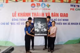 Đại diện Cơ quan thường trú TTXVN tại Thành phố Hồ Chí Minh tặng bức ảnh Chủ tịch Hồ Chí Minh cho Ủy ban Nhân dân xã Nhuận Đức, huyện Củ Chi. (Ảnh: Thu Hương/TTXVN)
