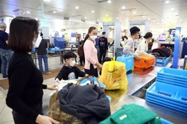 Hành khách xếp đồ để qua máy soi chiếu tại Cảng hàng không quốc tế Nội Bài. (Ảnh: Huy Hùng/TTXVN)