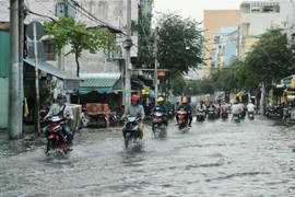 Người dân di chuyển giữa làn nước trên đường Huỳnh Tấn Phát ở quận 7. (Ảnh: Hồng Giang/TTXVN)