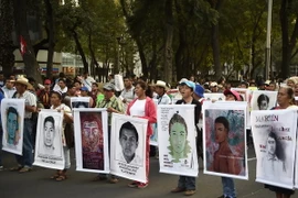 Thân nhân của 43 sinh viên mất tích và đại diện các tổ chức xã hội tham gia cuộc tuần hành ở Mexico City. (Nguồn: AFP/TTXVN)