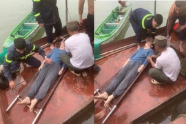 Lực lượng Cảnh sát Phòng cháy Chữa cháy và Cứu nạn Cứu hộ phối hợp với người dân thuyền chài tổ chức sơ cấp cứu cho nạn nhân. (Ảnh: Công an thành phố Hà Nội)
