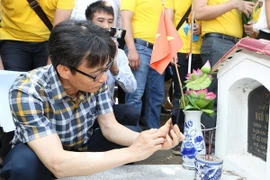 Phó Thủ tướng Vũ Đức Đam dùng thử ứng dụng thông tin điện tử về liệt sỹ, mộ liệt sỹ và nghĩa trang liệt sỹ trên điện thoại. (Ảnh: Dương Giang/TTXVN)