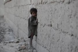Một em bé Afghanistan đứng dựa vào bức tường khu vực đổ nát do xung đột ở ngoại ô Kabul tháng 10/2011. (Nguồn: AFP/TTXVN)