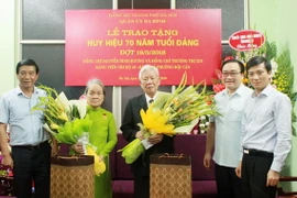 Bí thư Thành ủy Hà Nội Hoàng Trung Hải trao Huy hiệu 70 năm tuổi Đảng cho nguyên Phó Trưởng ban Tổ chức Trung ương Nguyễn Đình Hương và bà Trương Thị Xin, nguyên Giám đốc Xí nghiệp may Chiến Thắng. (Ảnh: TTXVN)