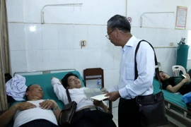 Ông Trần Công Thịnh, Tổng Lãnh sự Việt Nam tại Savannakhet, đang tặng quà và thăm hỏi các nạn nhân của vụ tai nạn. (Ảnh: Phạm Kiên/Vietnam+) 