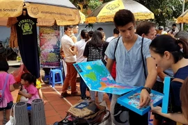 Cậu bé đang hướng dẫn sử dụng bộ đồ vừa học vừa chơi của trẻ em còn nguyên hộp cho người hỏi mua. (Ảnh: Ngọc Hà/TTXVN)