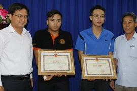 Lãnh đạo quận Thủ Đức trao bằng khen cho anh Dương Minh Quang và anh Bùi Văn Tiến. (Ảnh: Hoàng Hải/TTXVN)