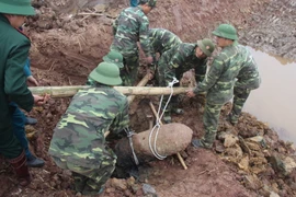 Lực lượng công binh tiến hành trục vớt quả bom nằm sâu dưới lòng đất. (Ảnh: Mai Ngoan/TTXVN)