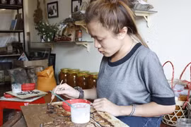 Võ Thị Thanh Thảo miệt mài hoàn thành một tác phẩm của mình. (Ảnh: Hồng Điệp/Vietnam+)
